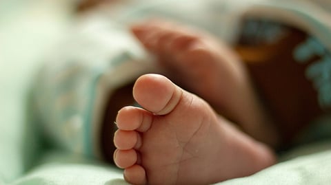 Close-up of a baby's foot resting on a soft surface in a warm, calm environment
