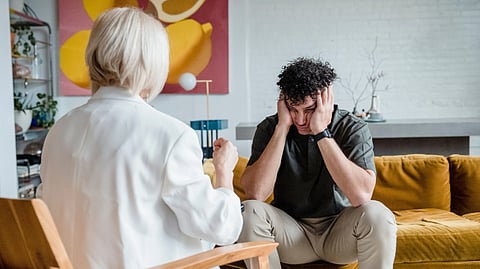 A therapist consults a distressed man in a cozy setting