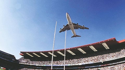 An airplane flying above a stadium.