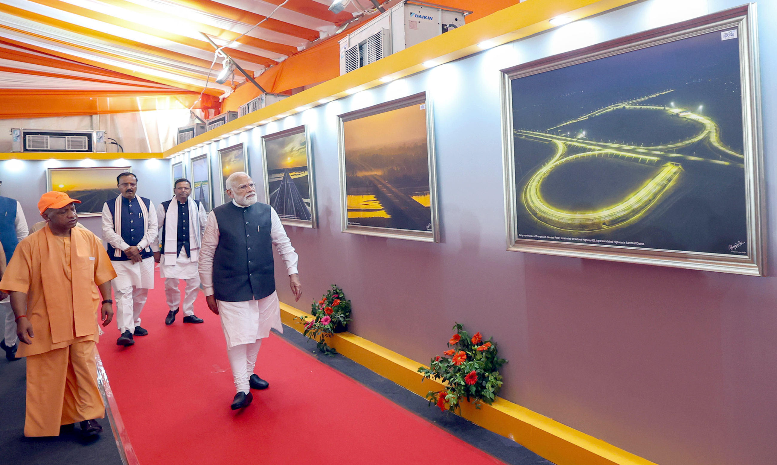 Prime Minister Narendra Modi, who arrived in Hardoi, Uttar Pradesh to inaugurate the 600-km Meerut-Prayagraj Ganga Expressway, views an exhibition displaying the road's design. Chief Minister Yogi Adityanath, Deputy Chief Ministers Keshav Prasad Maurya and Dinesh Sharma are seen nearby.