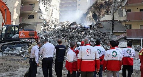 Iranian Red Crescent volunteers gather in front of a building destroyed in an Israeli strike in Tehran. 