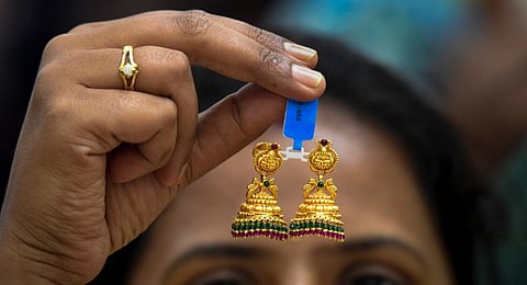 A customer holds a pair of earrings at a jewellery shop