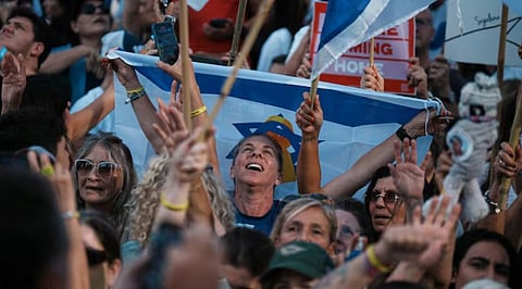 People react as they gather to watch a live broadcast of Israeli hostages released from Gaza at a plaza known as hostages square in Tel Aviv, Israel, Monday, Oct. 13, 2025.