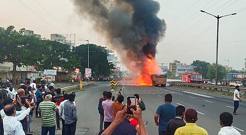 People stand near a burning car after an accident on the Mumbai-Bengaluru Highway, in Pune, Maharashtra, Thursday, Nov. 13, 2025. 