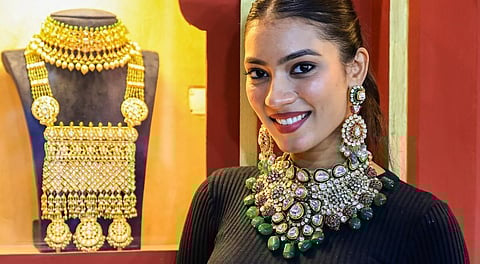 A model poses outside a jewellery stall during the 'Jaipur Jewellery Show 2025' at the Novotel Jaipur Convention Centre, in Jaipur, Sunday, Dec. 21, 2025.