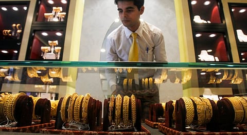 An employee displays gold ornaments at a jewellery showroom