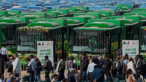 People gather near the buses at an event where Delhi Chief Minister Rekha Gupta, unseen, flagged off 500 new electric vehicle (EV) buses, in New Delhi, Sunday, Feb. 8, 2026.