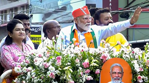 Prime Minister Narendra Modi greets supporters during a roadshow ahead of the Kerala Assembly elections, in Thrissur. Union Minister of State for Petroleum and Natural Gas Suresh Gopi and candidate Padmaja Venugopal are also seen.