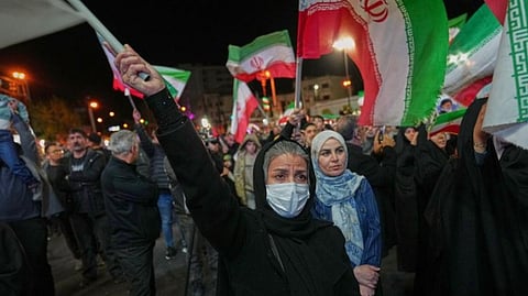 Women hold Iranian flags during a pro-government gathering in a square in Tehran, Iran. 