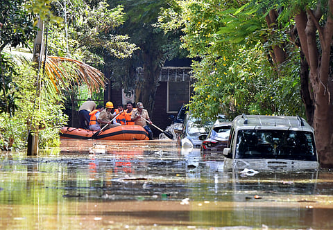 FILE PHOTO: Members of a rescue team row their boat past submerged vehicles following torrential rains in Bengaluru, India, September 5, 2022. 