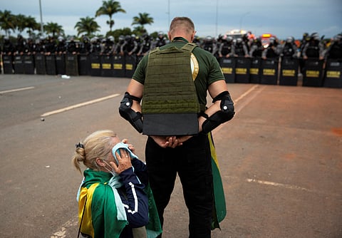 A supporter of Brazil's far-right former President Jair Bolsonaro who along with others disputes the election of leftist President Luiz Inacio Lula da Silva, shields a fellow supporter during protests, in Brasilia, Brazil January 8, 2023. 