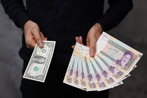 FILE PHOTO: A currency dealer poses for a photo with a U.S one dollar bill and the amount being given when converting it into Iranian rials in an exchange shop in Tehran, Iran December 25, 2022. 