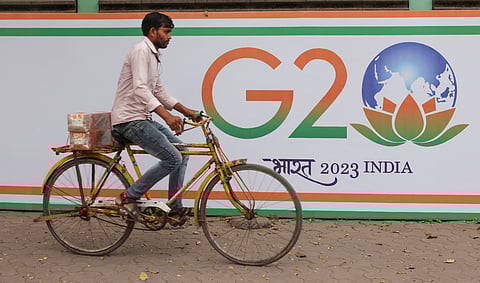 FILE PHOTO: A man rides a bicycle past the hoarding of India's G20 presidency, on a street in Mumbai, India, December 15, 2022. 