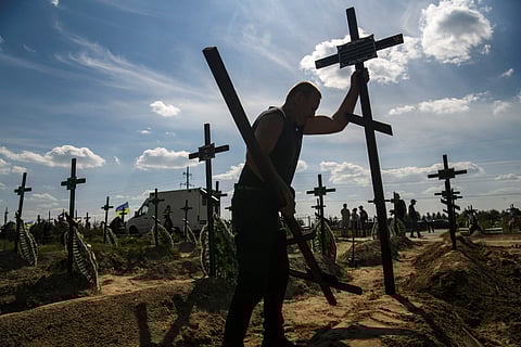 FILE PHOTO: A volunteer places a cross onto a grave of one of fifteen unidentified people killed by Russian troops, amid Russia's attack on Ukraine continues, during a burial ceremony in the town of Bucha, in Kyiv region, Ukraine September 2, 2022. 