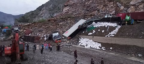 Rescue workers and people gather after trucks loaded with supplies were trapped in a landslide on the road close to the Torkham border, Pakistan April 18, 2023. 