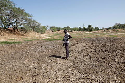 FILE PHOTO: Famine Early Warning System Network in Africa (FEWS NET) scientist Chris Shitote examines a dry water hole in Kilifi county, Kenya, February 16, 2022. 