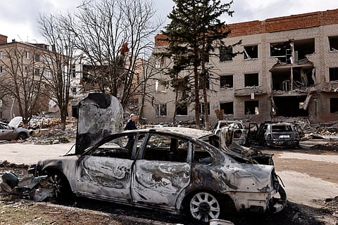 FILE PHOTO: A person walks next to a damaged car in the aftermath of deadly shelling of an army office building, amid Russia's attack, in Sloviansk, Ukraine, March 27, 2023. 