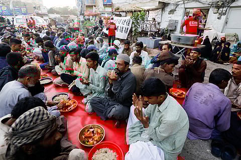 People gather to break their fast, organised by the Edhi Foundation, a non-profit social welfare programme, along a road in Karachi, Pakistan April 3, 2023. 