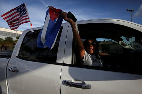FILE PHOTO: A woman shouts and waves a Cuban flag as drives past outside Versailles restaurant, where emigres gather in reaction to reports of protests in Cuba against its deteriorating economy, in Miami, Florida, U.S. July 18, 2021. 