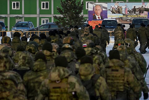 FILE PHOTO: Russian reservists recruited during a partial mobilisation of troops, aimed to support the country's military campaign in Ukraine, walks towards a banner with a portrait of Russian President Vladimir Putin during a ceremony before their departure in Omsk, Russia January 6, 2023. 