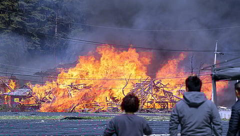 Residents look at buildings being burnt down by wildfire in Gangneung, South Korea, April 11, 2023. 