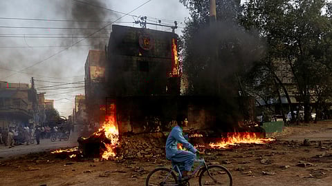 A boy rides past a paramilitary check post, that was set afire by the supporters of Pakistan's former Prime Minister Imran Khan, during a protest against his arrest, in Karachi, Pakistan May 9, 2023. 