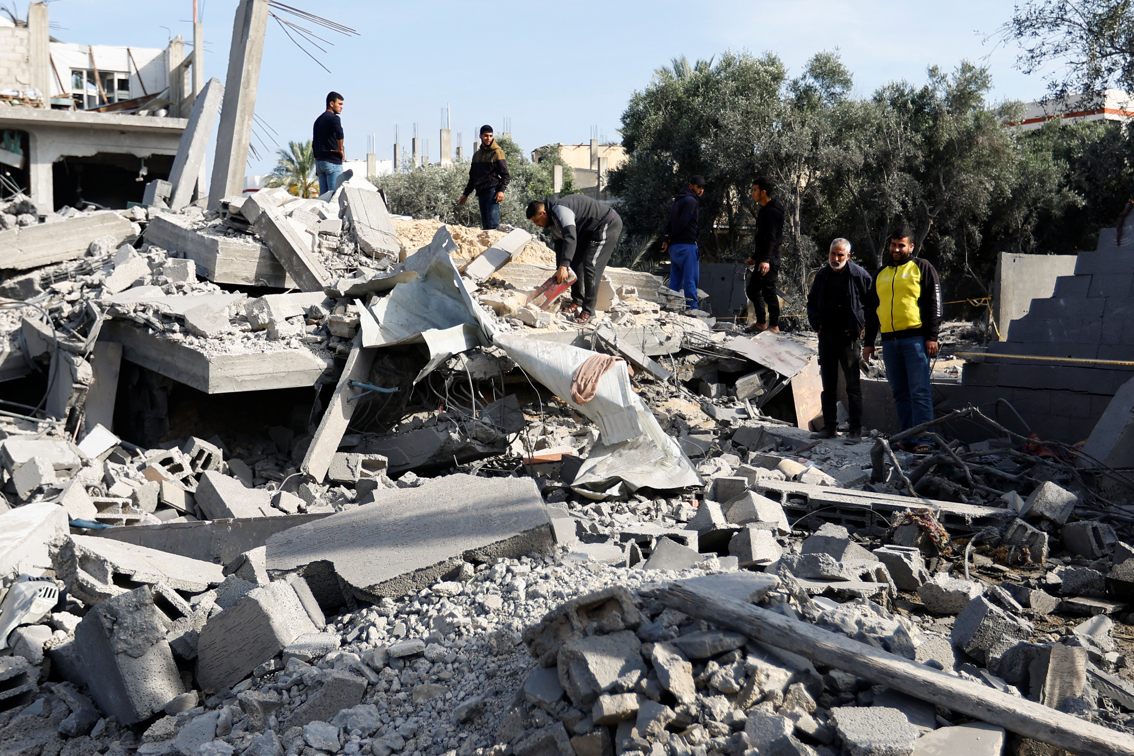 Palestinians stand on the remains of their destroyed houses, which were damaged in an Israeli strike during Israel-Gaza fighting, after a ceasefire was agreed between Palestinian factions and Israel, in Deir Al-Balah, central Gaza Strip May 14, 2023. 