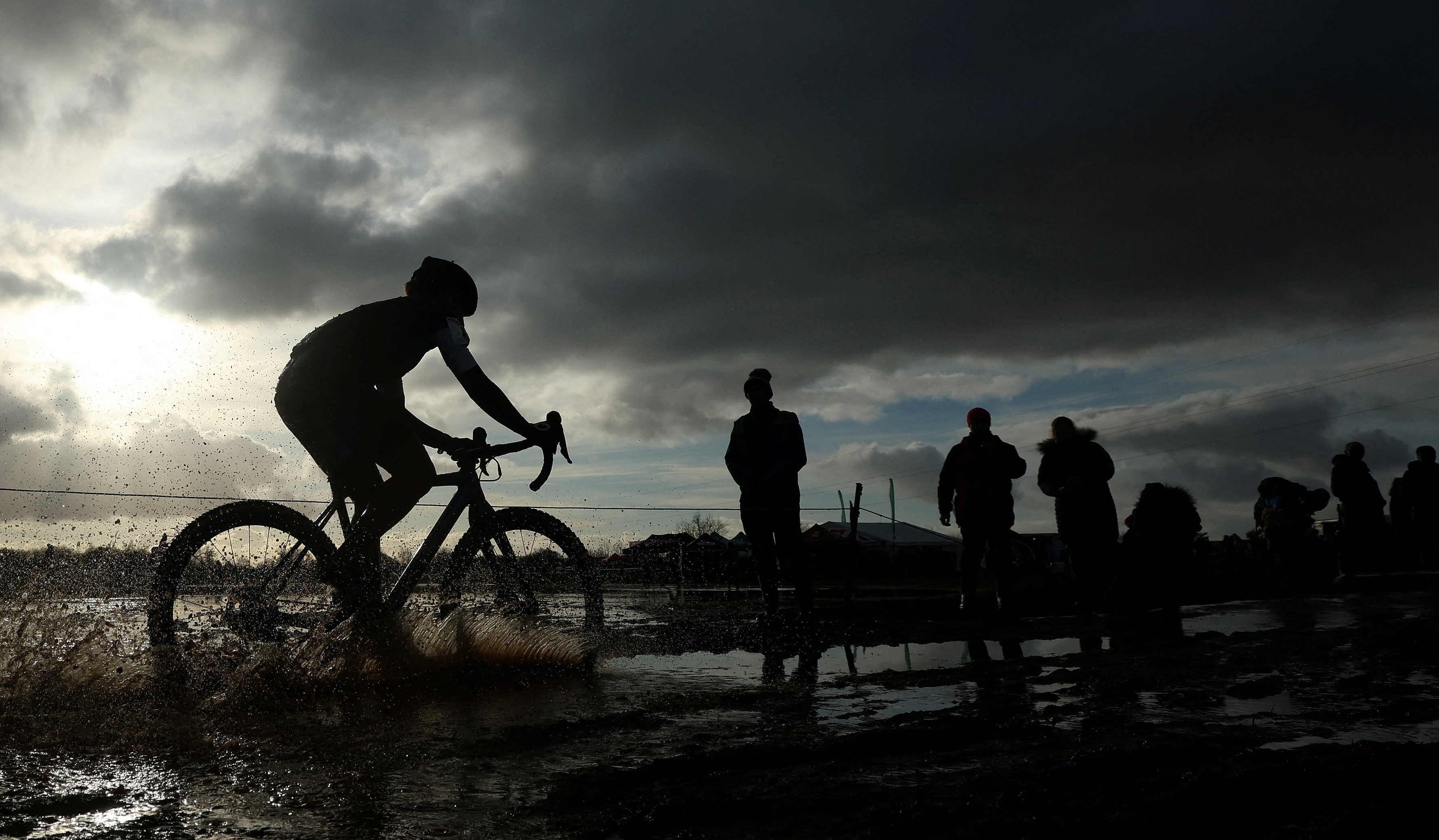 FILE PHOTO: A competitor cycles through a puddle during the Senior Women's race at the British Cyclocross championships near Milnthorpe, Britain, January 15, 2023. 