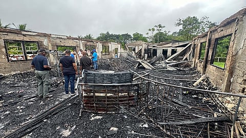 FILE PHOTO: People stand inside the remains of a burnt secondary school dormitory after several children, most of them from indigenous communities, died after a fire gutted the building overnight, in Mahdia, Guyana in this handout image obtained by Reuters on 22 May, 2023. 