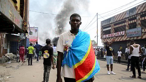 FILE PHOTO: An anti-government demonstrator wears a Democratic Republic of Congo flag as he takes part in a riot, after security forces broke up an attempted demonstration organized by the opposition and civil society members over alleged irregularities in voter registration for the upcoming December elections, in Kinshasa, Democratic Republic of Congo, May 20, 2023. 
