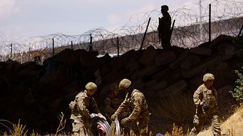Members of the Texas Army National Guard extend razor wire to inhibit migrants from crossing, as seen from Ciudad Juarez, Mexico May 13, 2023. 