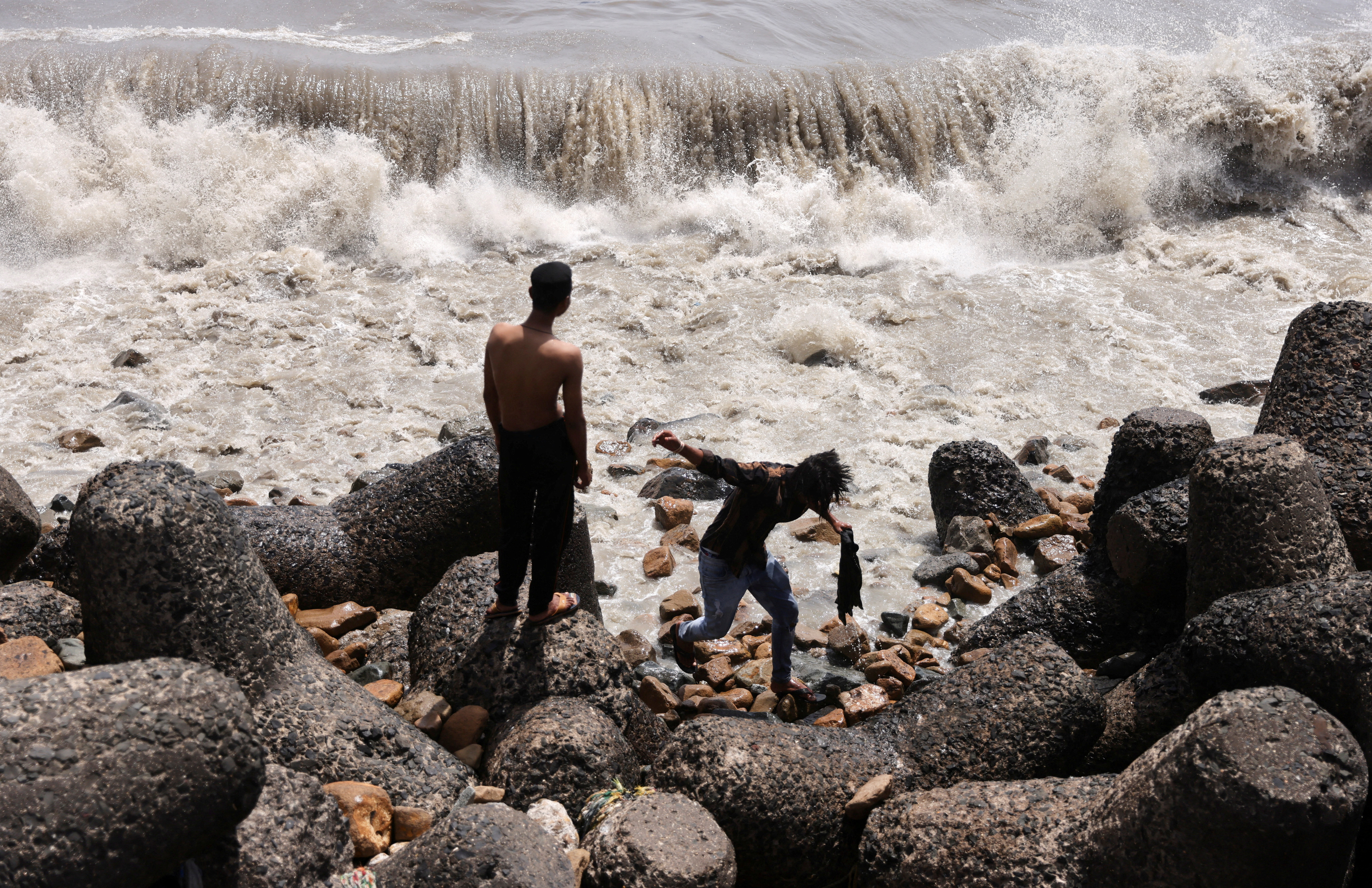 Boys watch waves hit the shore in Mumbai, India, June 12, 2023. 
