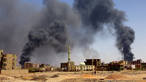 FILE PHOTO: A man walks while smoke rises above buildings after aerial bombardments during clashes between the paramilitary Rapid Support Forces and the army in Khartoum North, Sudan, May 1, 2023. 