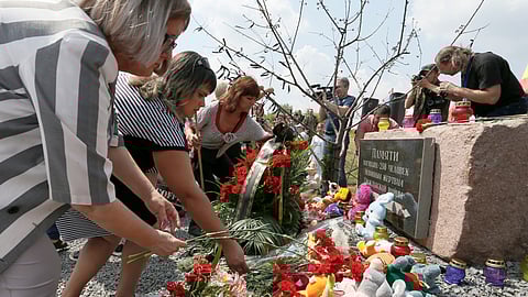 People place flowers and toys at a memorial to victims of the Malaysia Airlines Flight MH17 plane crash during a ceremony marking the fifth anniversary of the accident near the village of Hrabove in Donetsk Region, Ukraine July 17, 2019. 