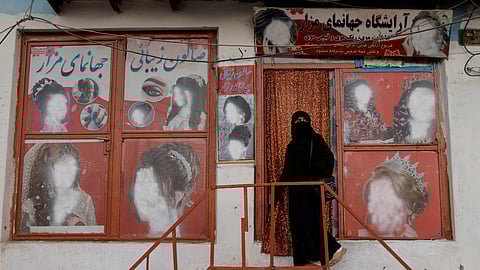 FILE PHOTO: A woman wearing a niqab enters a beauty salon where the ads of women have been defaced by a shopkeeper in Kabul, Afghanistan October 6, 2021. 