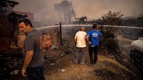 A municipal firefighting vehicle tries to extinguish a fire at the shipyard of Giorgos Barberakis, as a wildfire burns in Mandra, Greece, July 18, 2023. 
