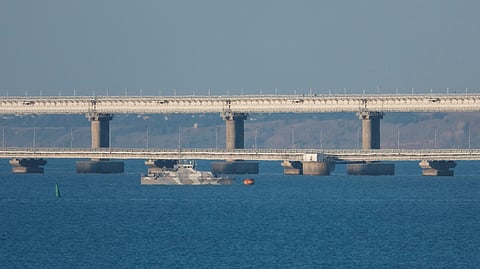 An armed ship sails next to Crimean bridge connecting the Russian mainland with the peninsula across the Kerch Strait, Crimea, July 17, 2023. 