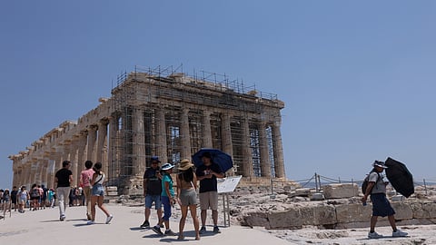 Visitors walk near the Parthenon temple, which sits atop Acropolis hill, during a heatwave in Athens, Greece, July 13, 2023. 