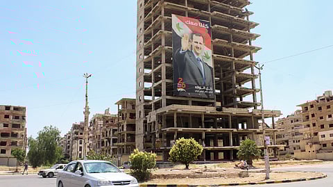 Vehicles pass near a poster depicting Syria's President Bashar al-Assad in Douma, Syria June 19, 2023. 