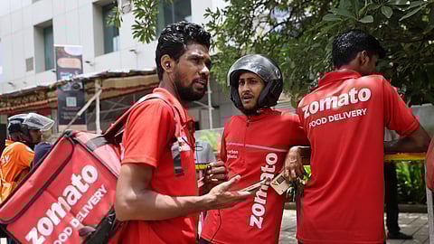 Gig workers wait in line to collect their delivery order outside a mall in Mumbai, India, August 10, 2023. 