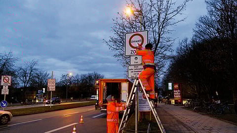 FILE PHOTO: A worker pulls the tape from a traffic sign indicating the ban on vehicles with Euro 5 diesel engines, on the Mittlerer Ring in Munich, Germany, February 1, 2023. 