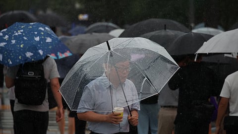 Commuters walk on a zebra crossing in the rain caused by typhoon Khanun in central Seoul, South Korea, August 10, 2023. 