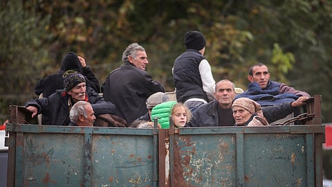 Refugees from Nagorno-Karabakh region ride in the back of a truck as they arrive in the border village of Kornidzor, Armenia, September 26, 2023. 