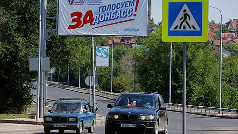FILE PHOTO: Cars drive past a banner reading "Let's vote for Donbas!" erected ahead of the upcoming regional elections planned by the Russian-installed authorities, in the course of Russia-Ukraine conflict in Donetsk, Russian-controlled Ukraine, August 14, 2023. 
