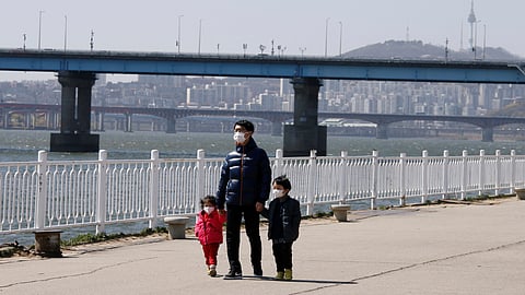 A man and children wearing masks to protect against contracting the coronavirus disease (COVID-19) take a walk at a Han River Park in Seoul, South Korea April 4, 2020. 
