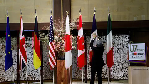 An official adjusts the flags before G7 foreign ministers gather for a family photo during their meetings in Tokyo, Japan, November 8, 2023. 