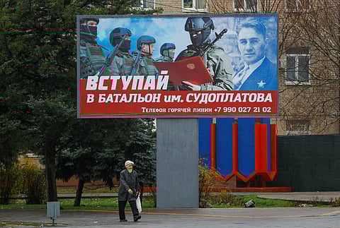 FILE PHOTO: A local resident walks past a board encouraging to join a Russian army battalion in the course of Russia-Ukraine conflict in Melitopol, Russian-controlled Ukraine, November 27, 2022. A slogan on the board reads: "Join battalion named after Sudoplatov". 