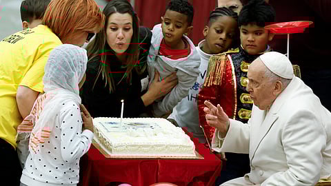 Pope Francis blows a candle on his cake for his 87th birthday, as he meets with a group of sick children from the "Santa Marta" Paediatric Dispensary at the Vatican, December 17, 2023. 