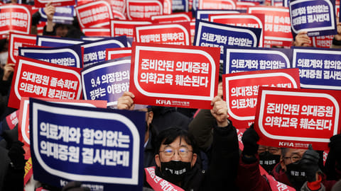 FILE PHOTO: Doctors chant slogans during a rally to protest against government plans to increase medical school admissions in Seoul, South Korea, March 3, 2024. The banners read "Oppose increasing medical school admissions without talks with the medical community" (in blue) and "Medical education will be harmed in increasing medical school admissions" (in red). 