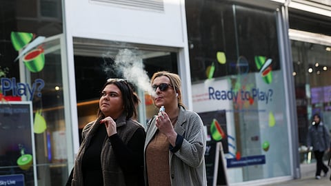 FILE PHOTO: A woman holds an e-cigarette as she vapes on a street in Manchester, Britain March 6, 2024. 